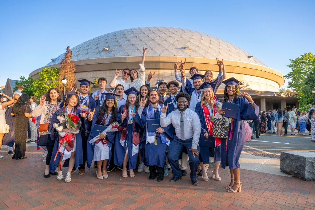 Group of College of Liberal Arts and Sciences graduates posing in front of Gampel Pavilion.