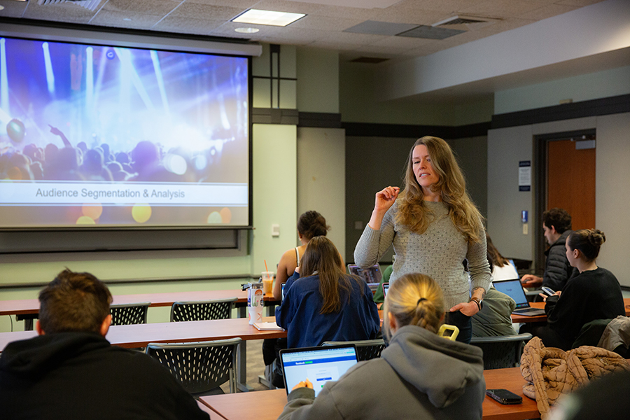 A communication professor stands in a classroom in Wilson Residence Hall.