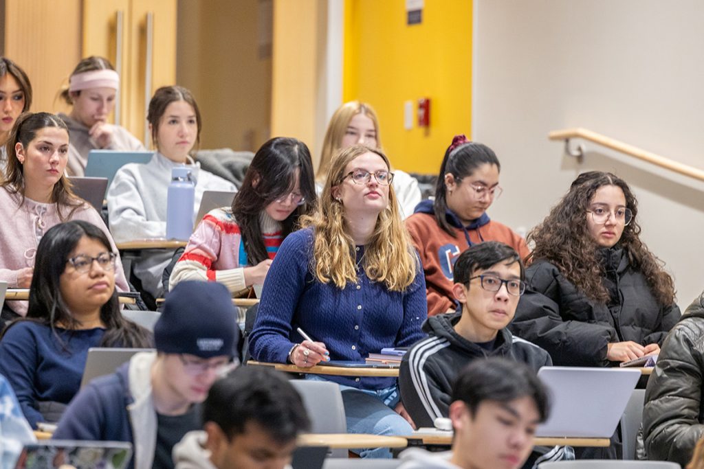 Students in a large lecture hall take notes during a class. 