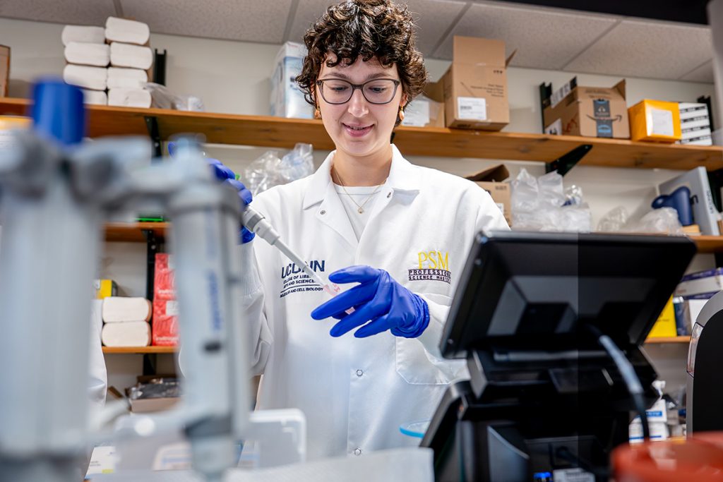 A graduate student works in a lab while wearing a lab coat.