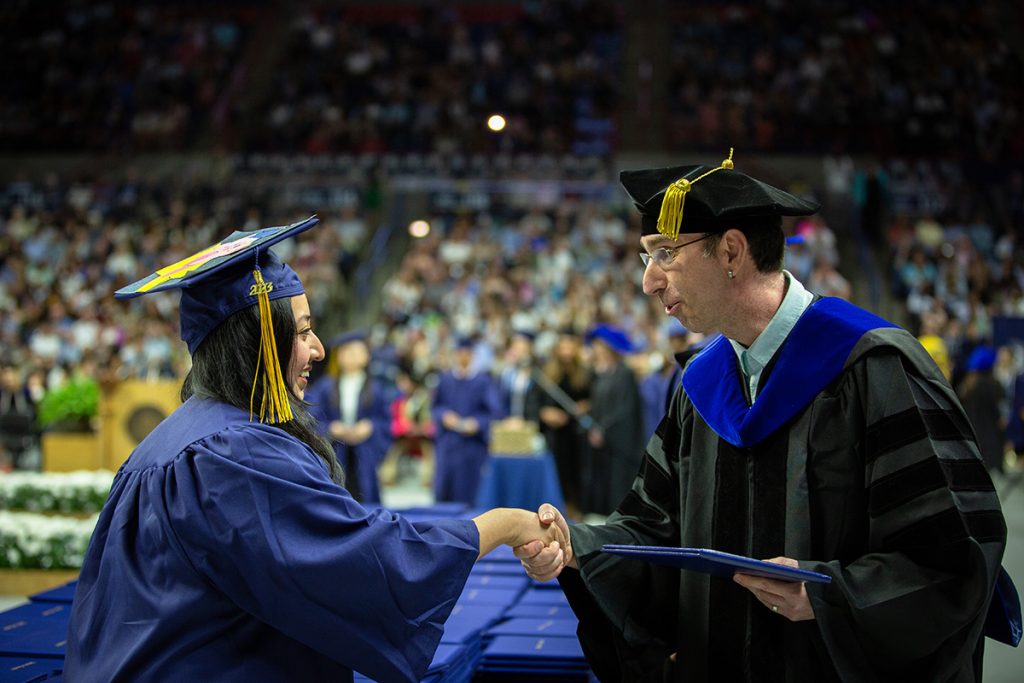Ofer Harel, dean of CLAS, hands out diplomas at commencement. 