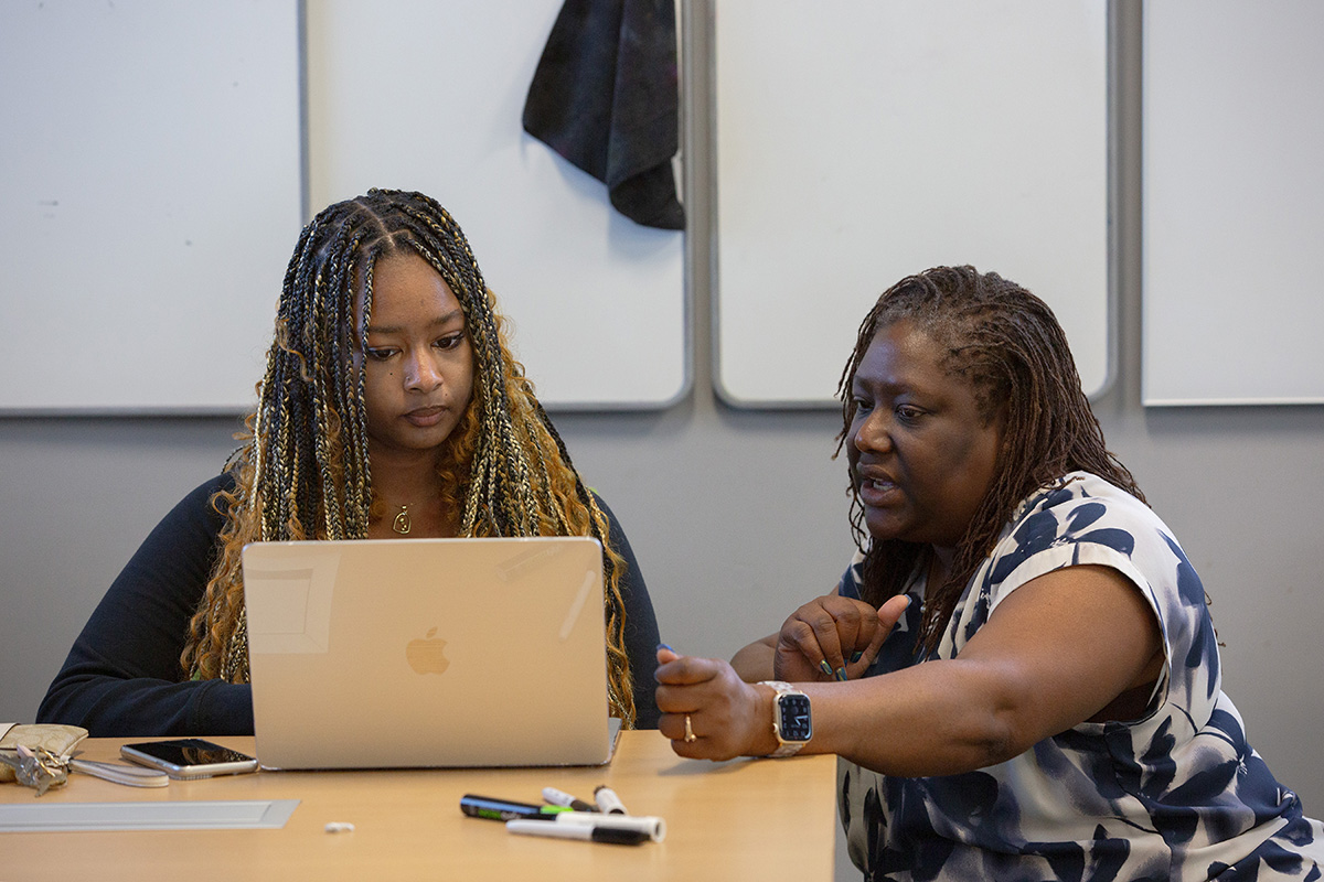 An advisor crouches next to a student to discuss.