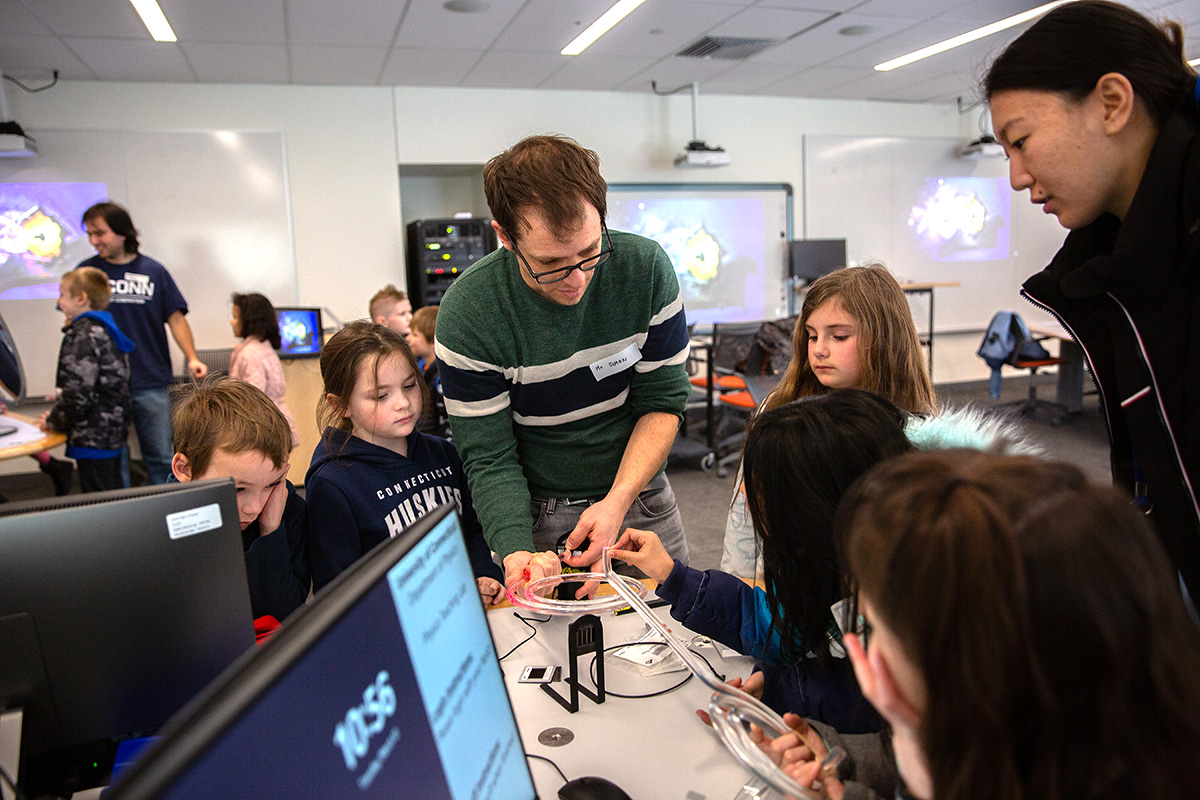 A physics professor works with elementary school children during an outreach event.