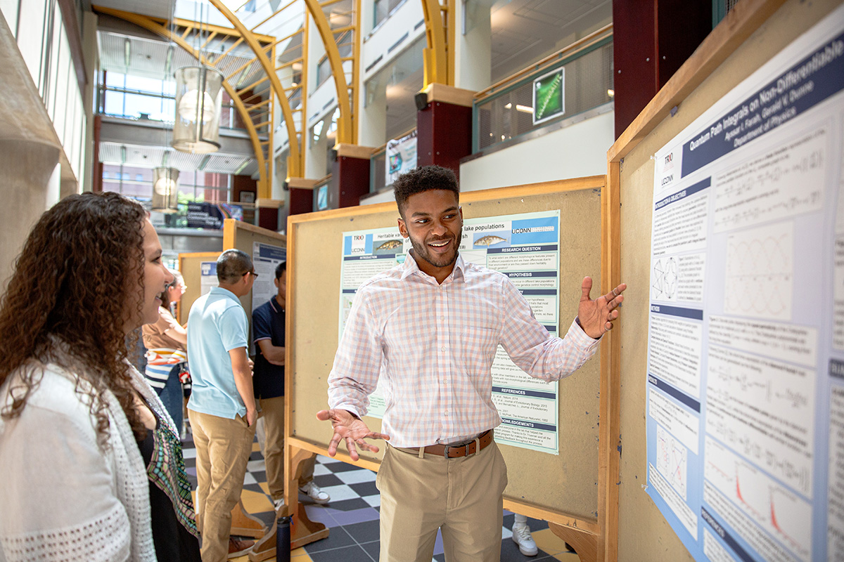 A student speaks about their research poster at an event.